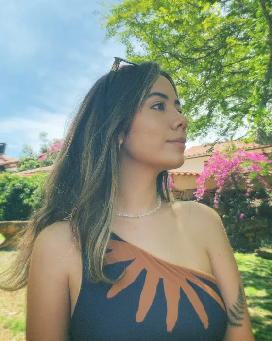 Camila Reyyes, psicóloga, al aire libre entre árboles y flores